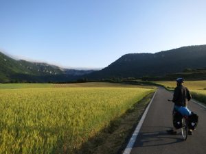 Cyclist on empty road with hills in background