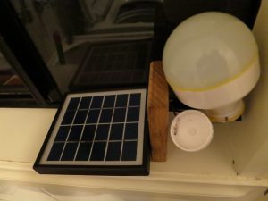 Battery powered lamp attached to small solar panel