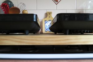 Portable induction hot plates resting on timber which is supported by unused gas stovetop